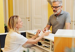 A man paying his dentist for sleep apnea treatment