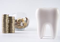 Tooth next to a bowl of coins