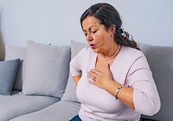 Woman with hand over her heart, wearing concerned expression