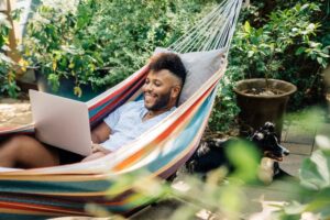 man sitting and relaxing in a hammock with his laptop