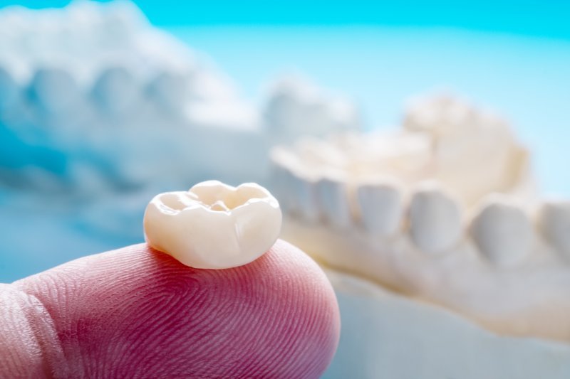 A dental crown sitting on a person’s finger